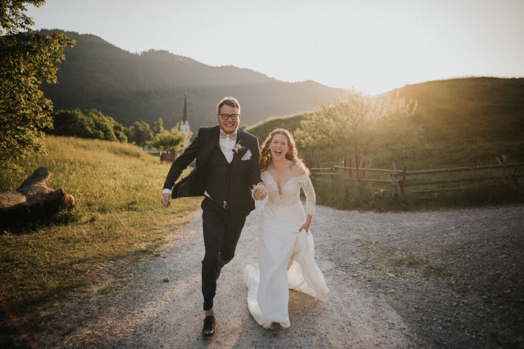 hochzeitspaar läuft freudestrahlend im sonnenuntergang auf die kamera vom hochzeitsfotograf münchen zu