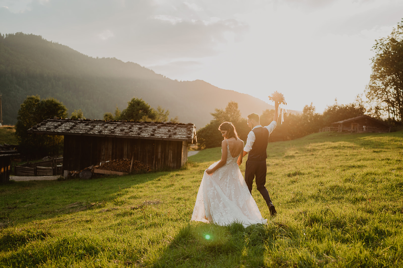 hochzeitspaar läuft freudestrahlend im sonnenuntergang vor der kamera vom hochzeitsfotograf münchen