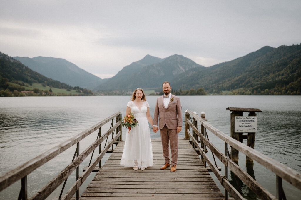 Hochzeitspaar steht am Steg am Schliersee im Herbst